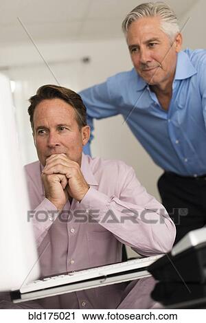 Stock Image - Caucasian businessmen working at computer. Fotosearch
