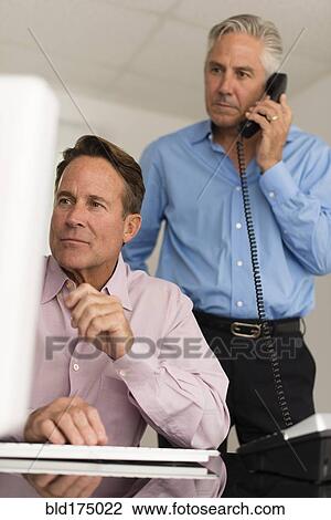 Stock Image - Caucasian businessmen working at computer. Fotosearch