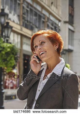 Stock Photograph - Caucasian businesswoman talking on cell phone in city. Fotosearch