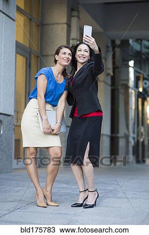 Caucasian businesswomen taking selfie outdoors View Large Photo Image Stock Image - Caucasian businesswomen taking selfie outdoors. Fotosearch