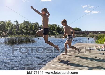 Picture - Caucasian children jumping into lake. Fotosearch
