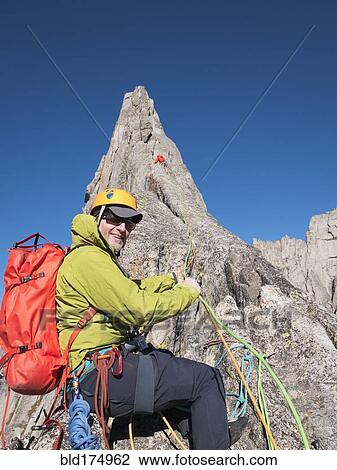 Stock Image - Caucasian climber smiling on mountainside. Fotosearch