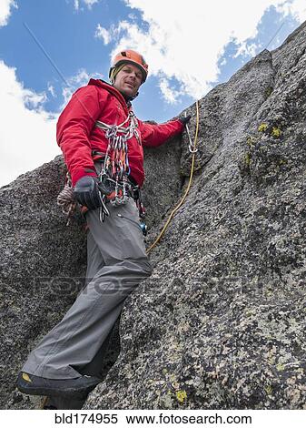 Stock Photography - Caucasian climber using rope on rock. Fotosearch