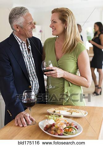 Stock Photograph - Caucasian couple drinking wine at party. Fotosearch