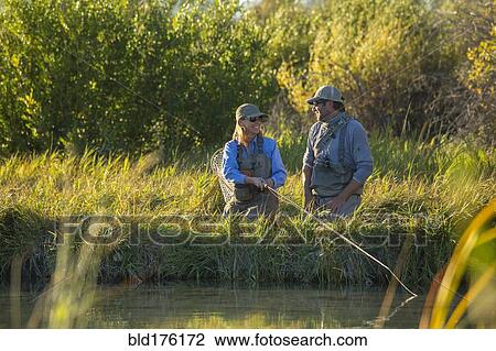 Stock Image - Caucasian couple fishing in river. Fotosearch