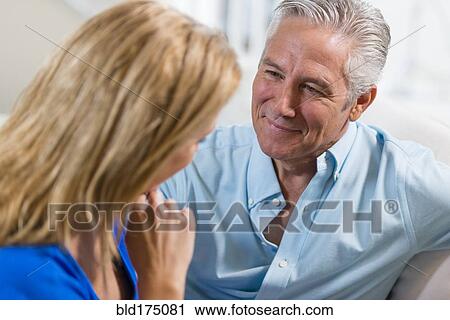 Stock Image - Caucasian couple talking on sofa. Fotosearch