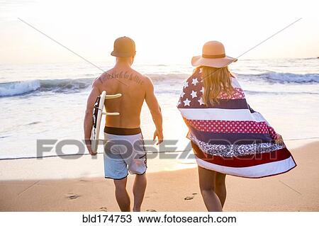 Stock Image - Caucasian couple walking on beach. Fotosearch