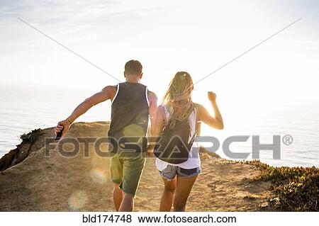 Stock Photo - Caucasian couple walking on cliff. Fotosearch
