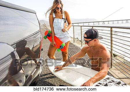 Caucasian couple waxing surfboard View Large Photo Image Stock Photograph - Caucasian couple waxing surfboard. Fotosearch