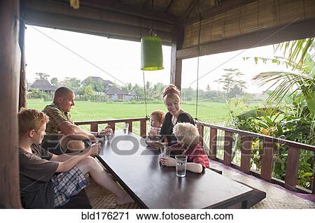 Stock Image - Caucasian family eating in covered patio. Fotosearch