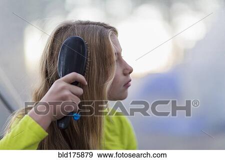 Stock Photo - Caucasian girl brushing her hair outdoors. Fotosearch