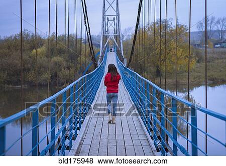 Caucasian girl walking on bridge View Large Photo Image Stock Photo - Caucasian girl walking on bridge. Fotosearch