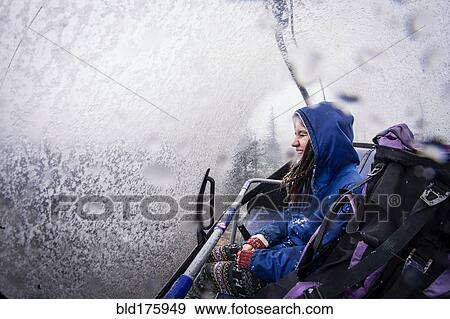 Stock Photo - Caucasian hiker riding ski lift. Fotosearch