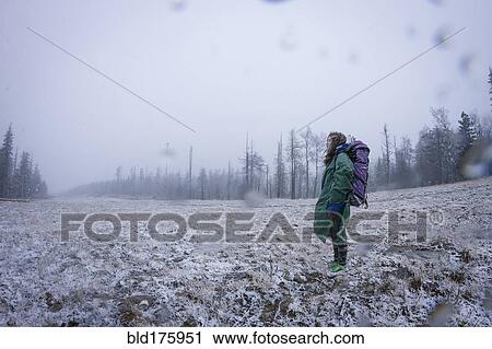 Stock Image - Caucasian hiker standing in frosty field. Fotosearch
