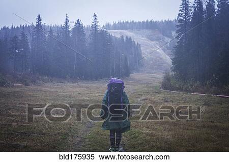 Stock Photography - Caucasian hiker standing on remote road. Fotosearch