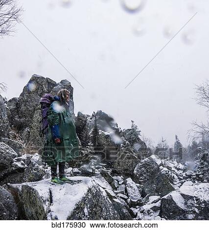 Stock Image - Caucasian hiker standing on rocky hillside. Fotosearch