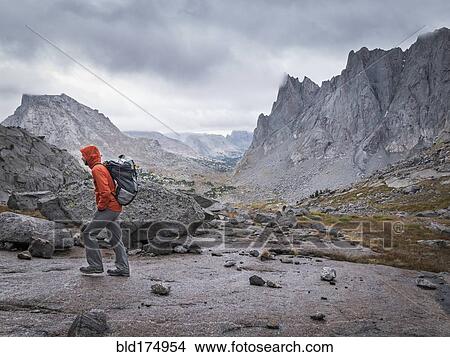 Picture - Caucasian hiker walking near mountains. Fotosearch