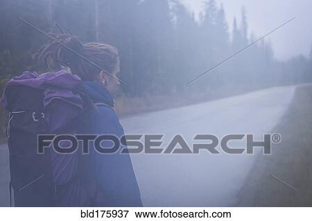 Stock Photo - Caucasian hiker walking on remote road. Fotosearch
