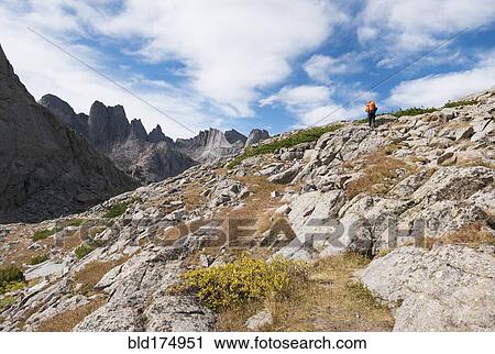Stock Image - Caucasian hiker walking on rocky hillside. Fotosearch