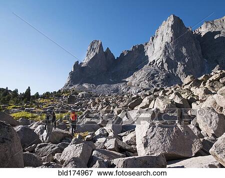 Stock Photo - Caucasian hikers walking in rocky field. Fotosearch