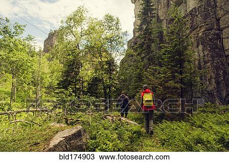 Stock Image - Caucasian hikers walking near mountain. Fotosearch