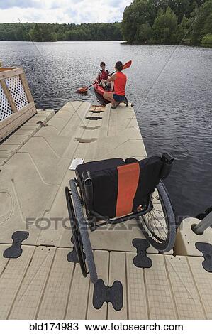 Stock Image - Caucasian instructor helping paraplegic woman with kayak. Fotosearch