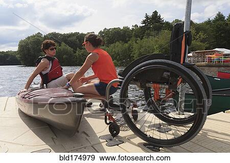 Stock Photo - Caucasian instructor helping paraplegic woman with kayak. Fotosearch