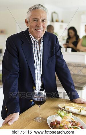 Stock Photography - Caucasian man drinking wine at party. Fotosearch