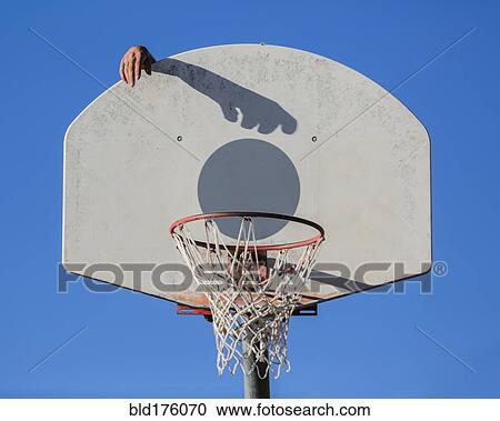 Stock Image - Caucasian man dunking basketball shadow in hoop. Fotosearch
