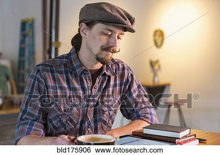 Stock Photograph - Caucasian man reading in cafe. Fotosearch