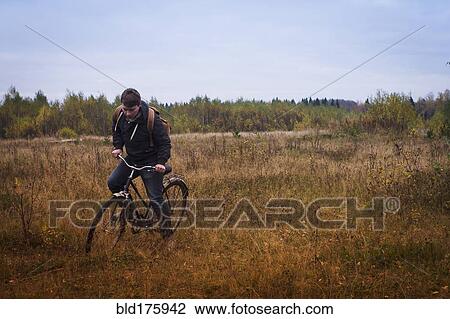 Caucasian man riding bicycle in field View Large Photo Image Stock Image - Caucasian man riding bicycle in field. Fotosearch