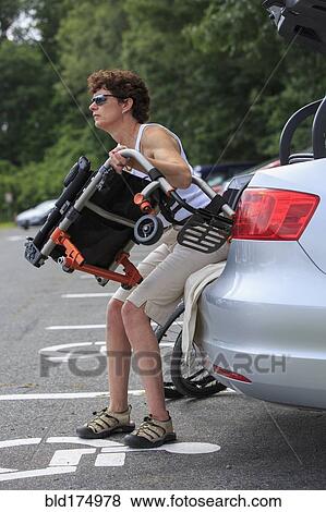 Stock Photo - Caucasian paraplegic woman unloading wheelchair from car. Fotosearch