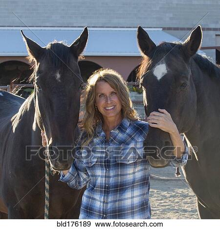 Stock Photo - Caucasian rancher smiling with horses. Fotosearch