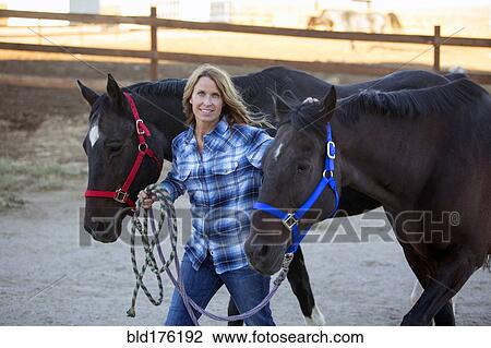 Stock Image - Caucasian rancher walking horses. Fotosearch