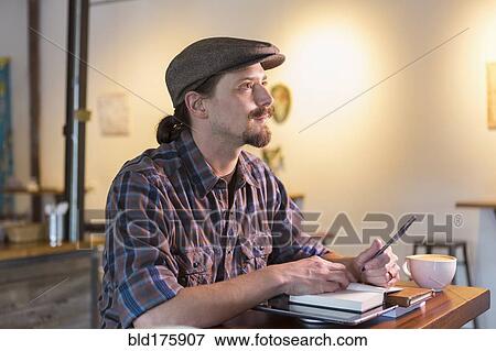 Stock Photo - Caucasian student doing homework in cafe. Fotosearch