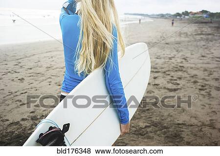 Stock Photo - Caucasian surfer carrying surfboard on beach. Fotosearch