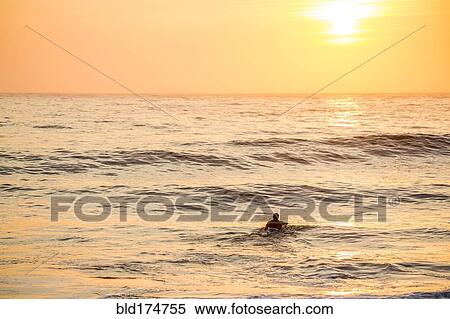 Stock Photography - Caucasian surfer swimming in waves. Fotosearch