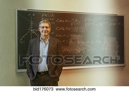 Stock Image - Caucasian teacher standing at chalkboard. Fotosearch