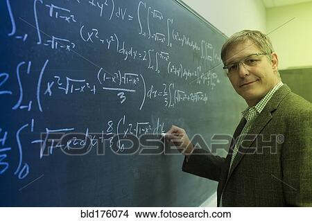 Picture - Caucasian teacher writing on chalkboard. Fotosearch