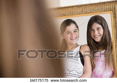 Caucasian twin sisters admiring themselves in mirror View Large Photo Image Stock Photography - Caucasian twin sisters admiring themselves in mirror. Fotosearch