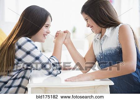 Stock Image - Caucasian twin sisters arm wrestling. Fotosearch
