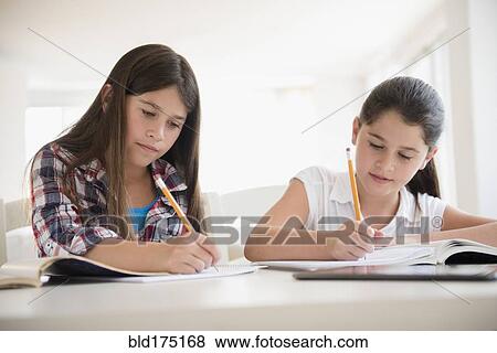 Stock Photo - Caucasian twin sisters doing homework. Fotosearch