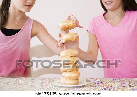 Stock Photography - Caucasian twin sisters eating donuts. Fotosearch