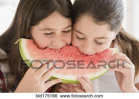 Stock Photograph - Caucasian twin sisters eating watermelon. Fotosearch
