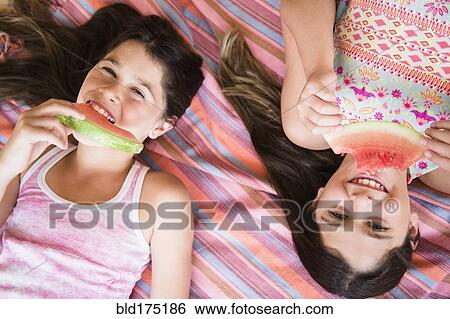 Stock Photograph - Caucasian twin sisters eating watermelon. Fotosearch