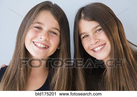 Stock Image - Caucasian twin sisters smiling. Fotosearch