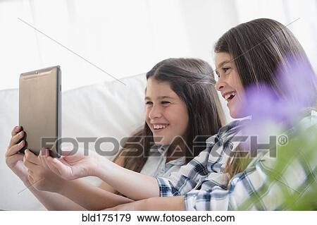 Stock Photo - Caucasian twin sisters using digital tablet. Fotosearch