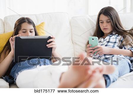 Caucasian twin sisters using technology View Large Photo Image Stock Photo - Caucasian twin sisters using technology. Fotosearch