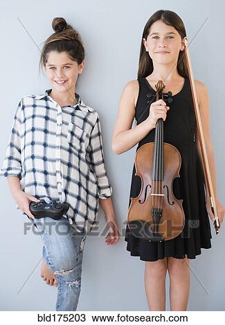 Stock Image - Caucasian twin sisters with opposite hobbies. Fotosearch