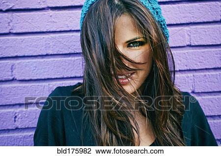 Stock Image - Caucasian woman at purple brick wall. Fotosearch